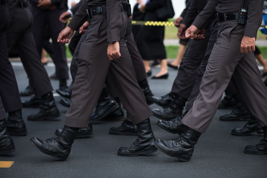 The boots of a group of police officers walking on the street.
