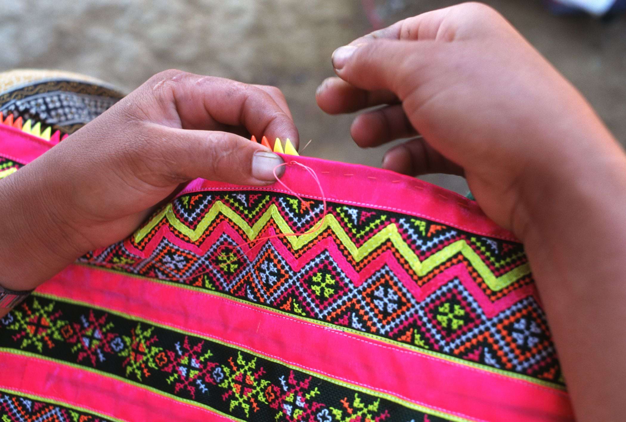 A close-up image of a women embroidering cloth.