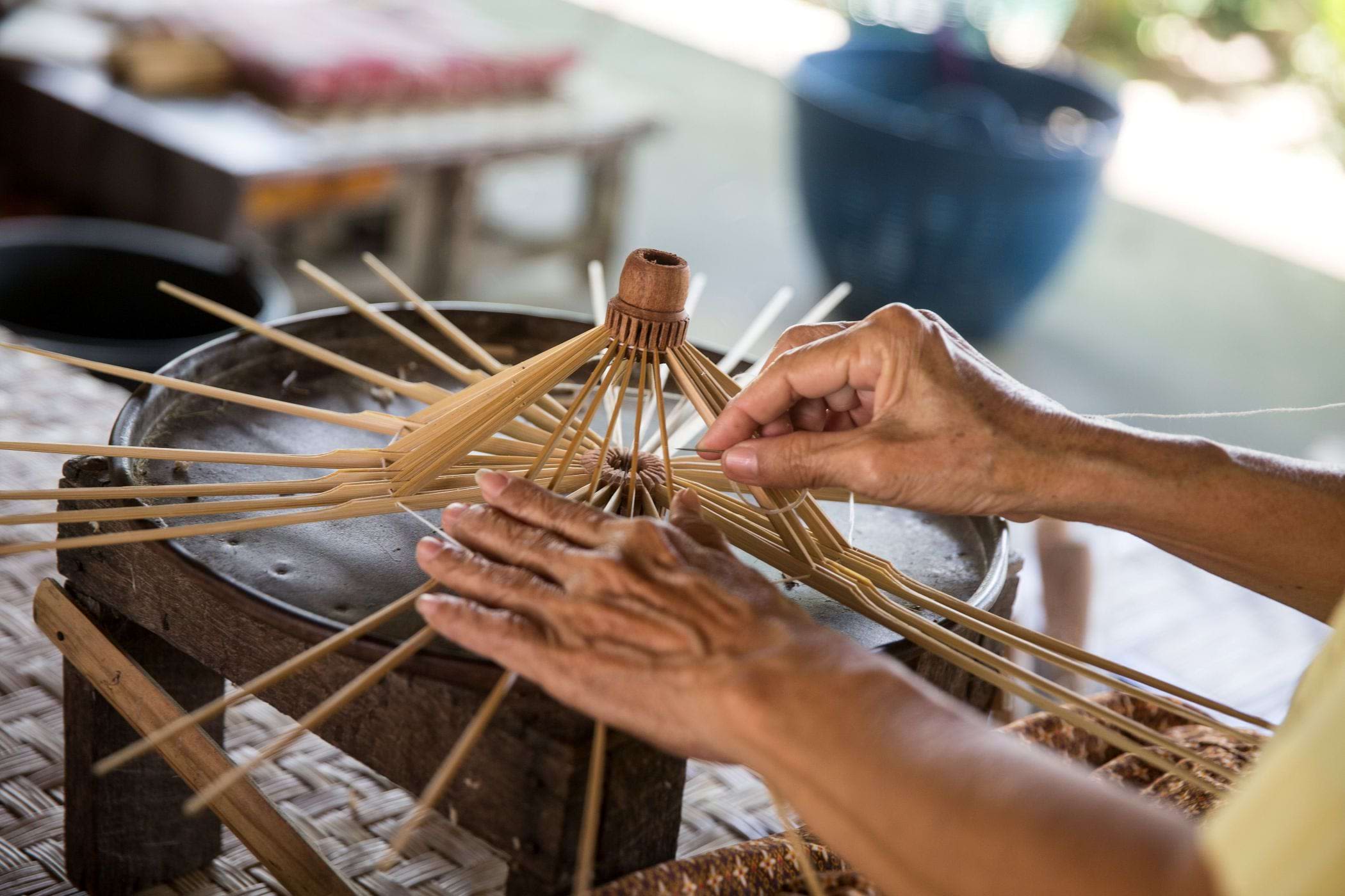 A close-up of the hands of a Thai craftswoman as she assembles an umbrella.