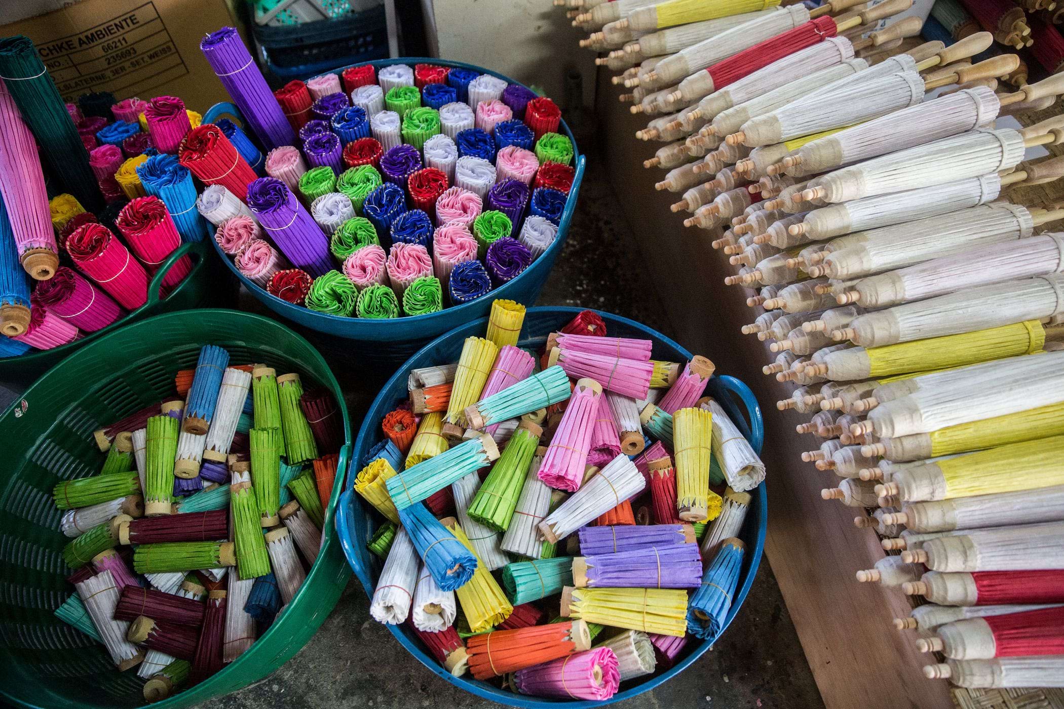 An overhead view of color pieces of mulberry paper umbrellas sitting in buckets.