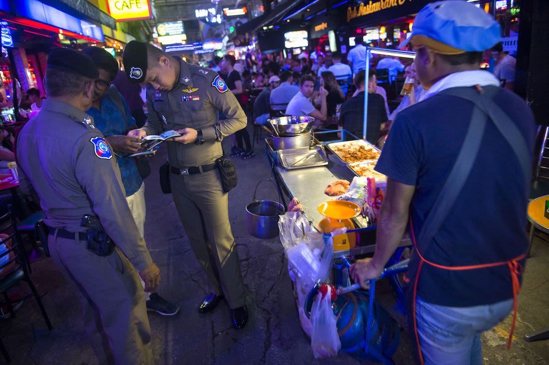 Two Thai police officers inspecting a passport