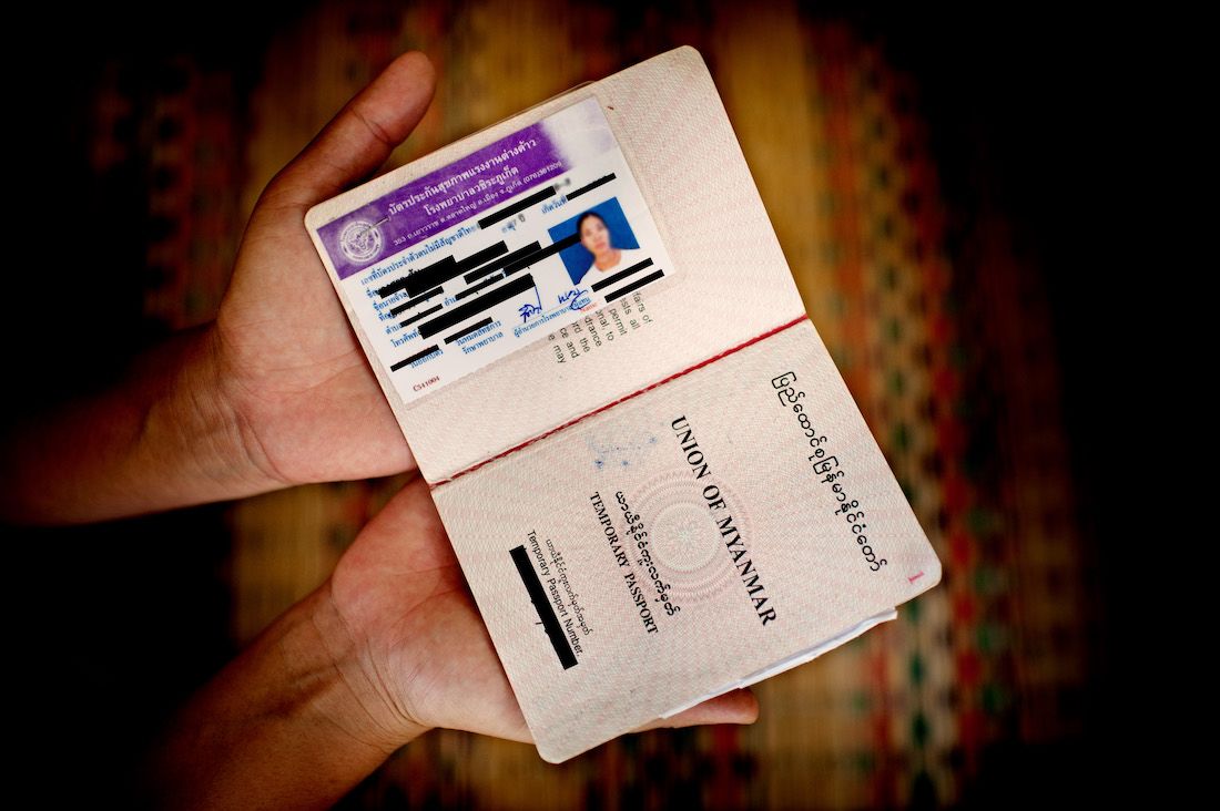 A migrant worker from Myanmar shows her work visa inside her passport.