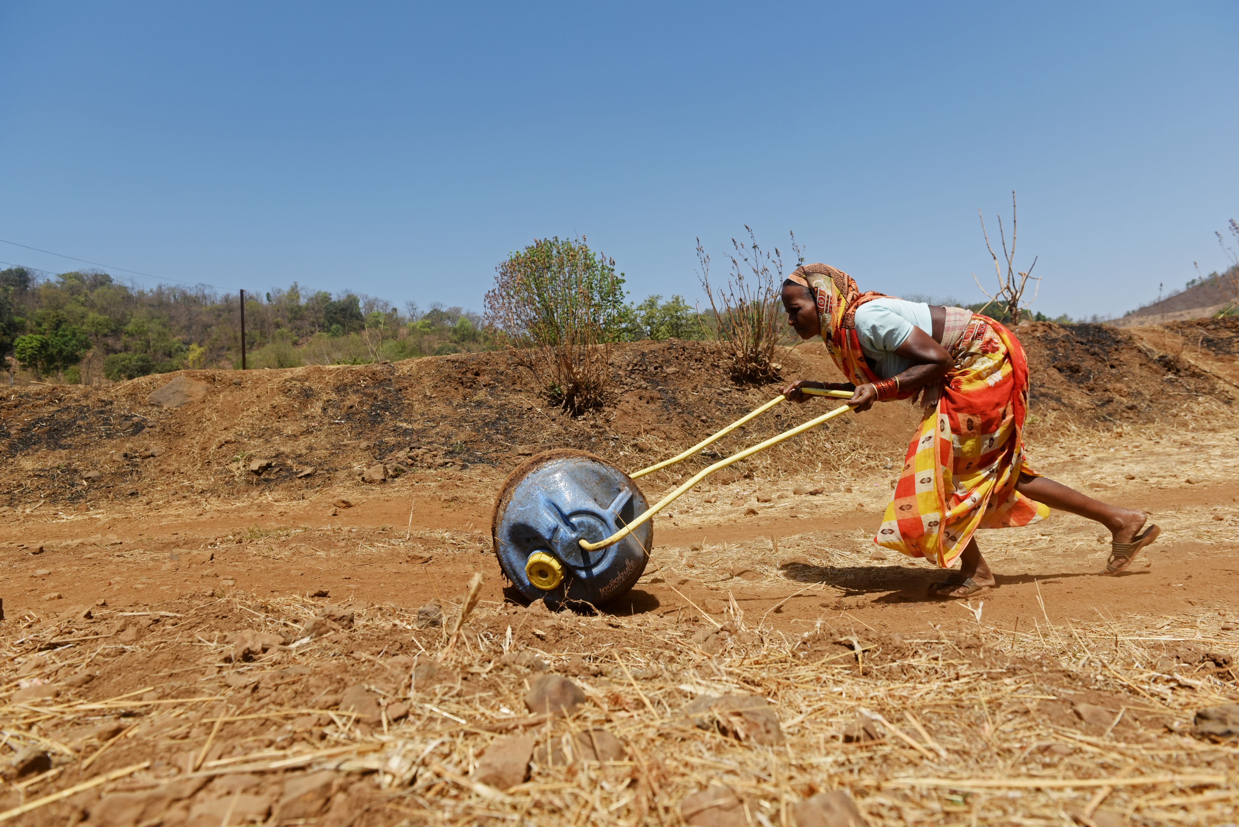 A woman pushing a water roller tank towards her home after drawing water from a well during the heatwave in Kasara, India, on May 1, 2024.  | Indranil Aditya/NurPhoto via Getty Images