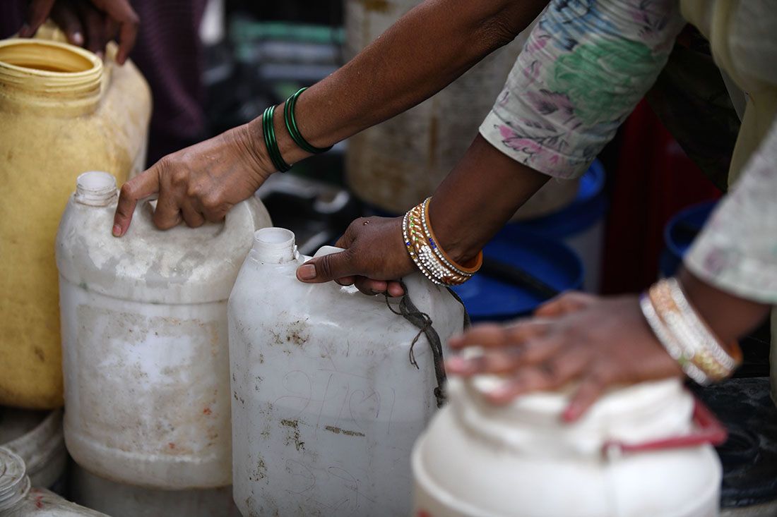 Women wait for fresh water at a water distribution point in Sanjay camp in New Delhi, India. | Dominque Faget/AFP via Getty Images