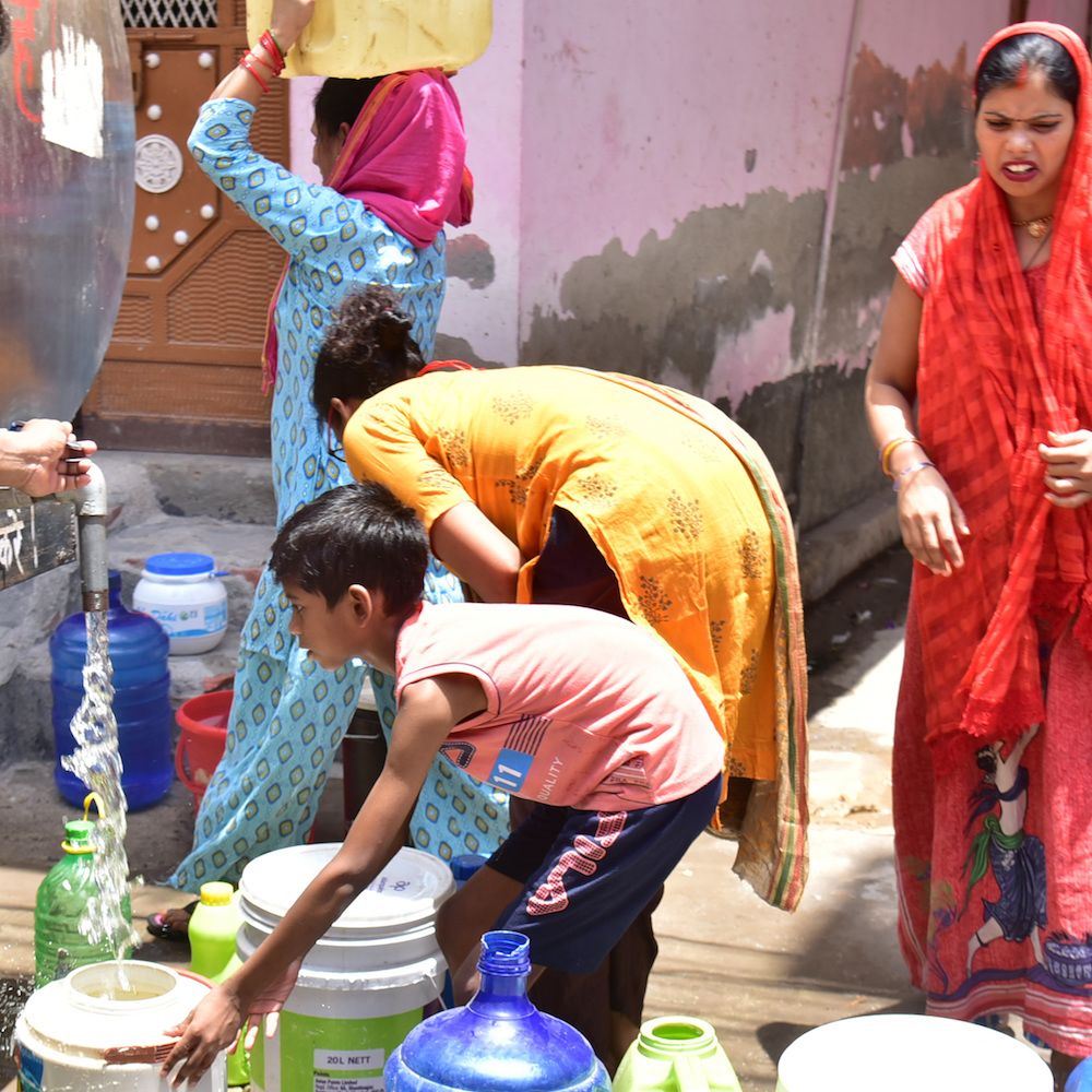 People gather water from a pump.