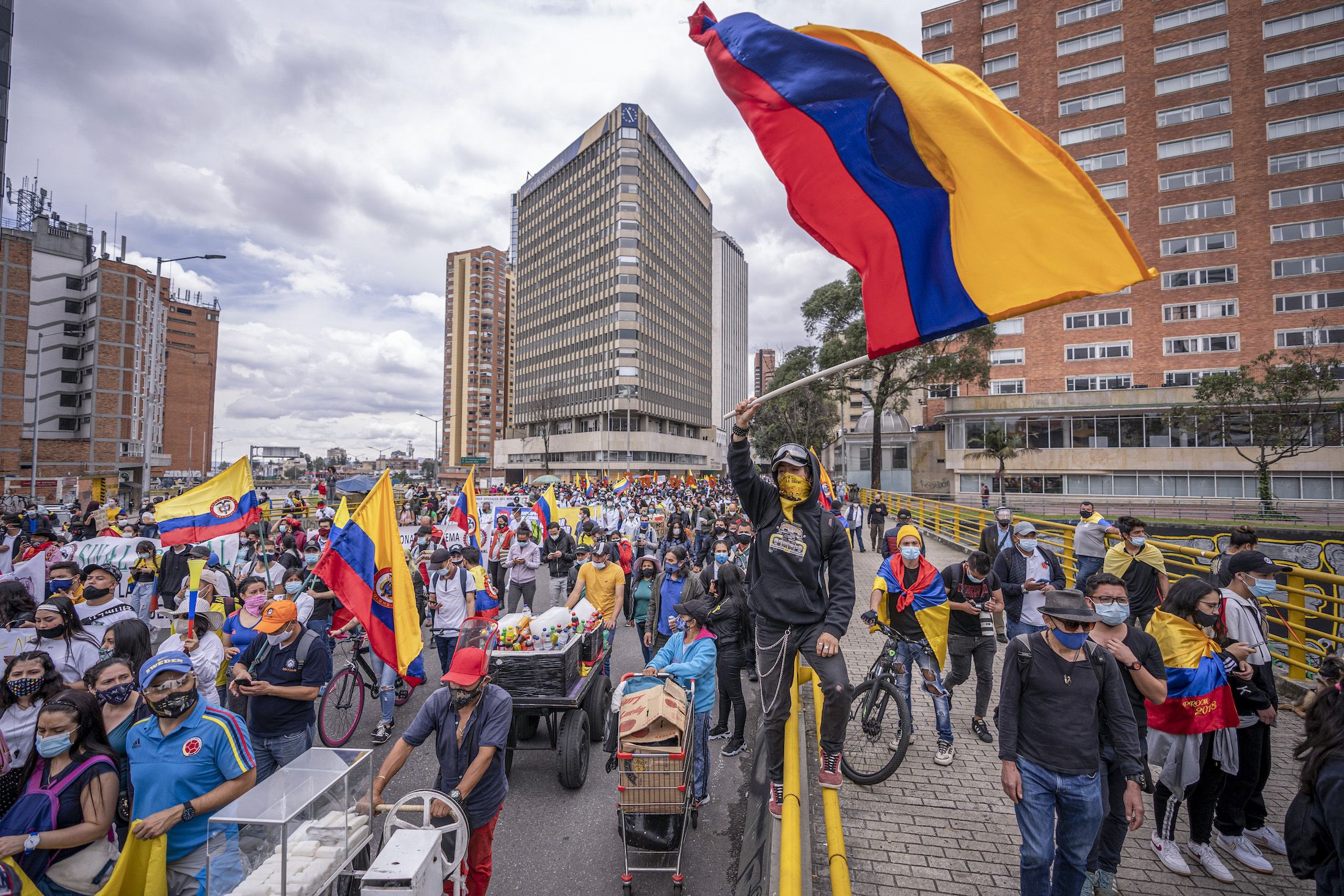 A demonstrator waves a Colombian flag while others walk by as part of a march during national strike on May 5, 2021 in Bogota, Colombia.