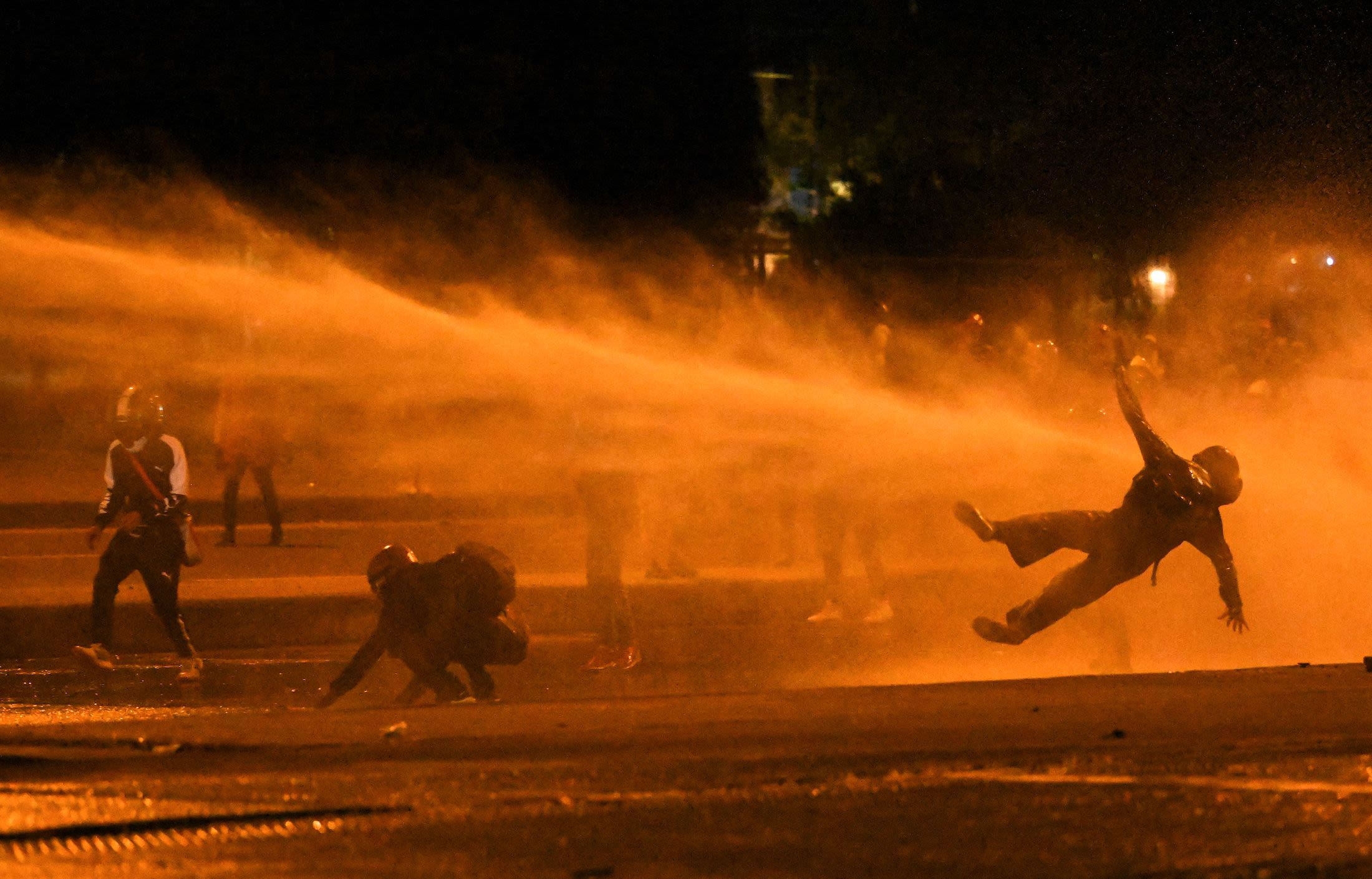 Protestors are hit by water cannons during clashes with riot police protesting former President Duque in Bogota in June 2021.