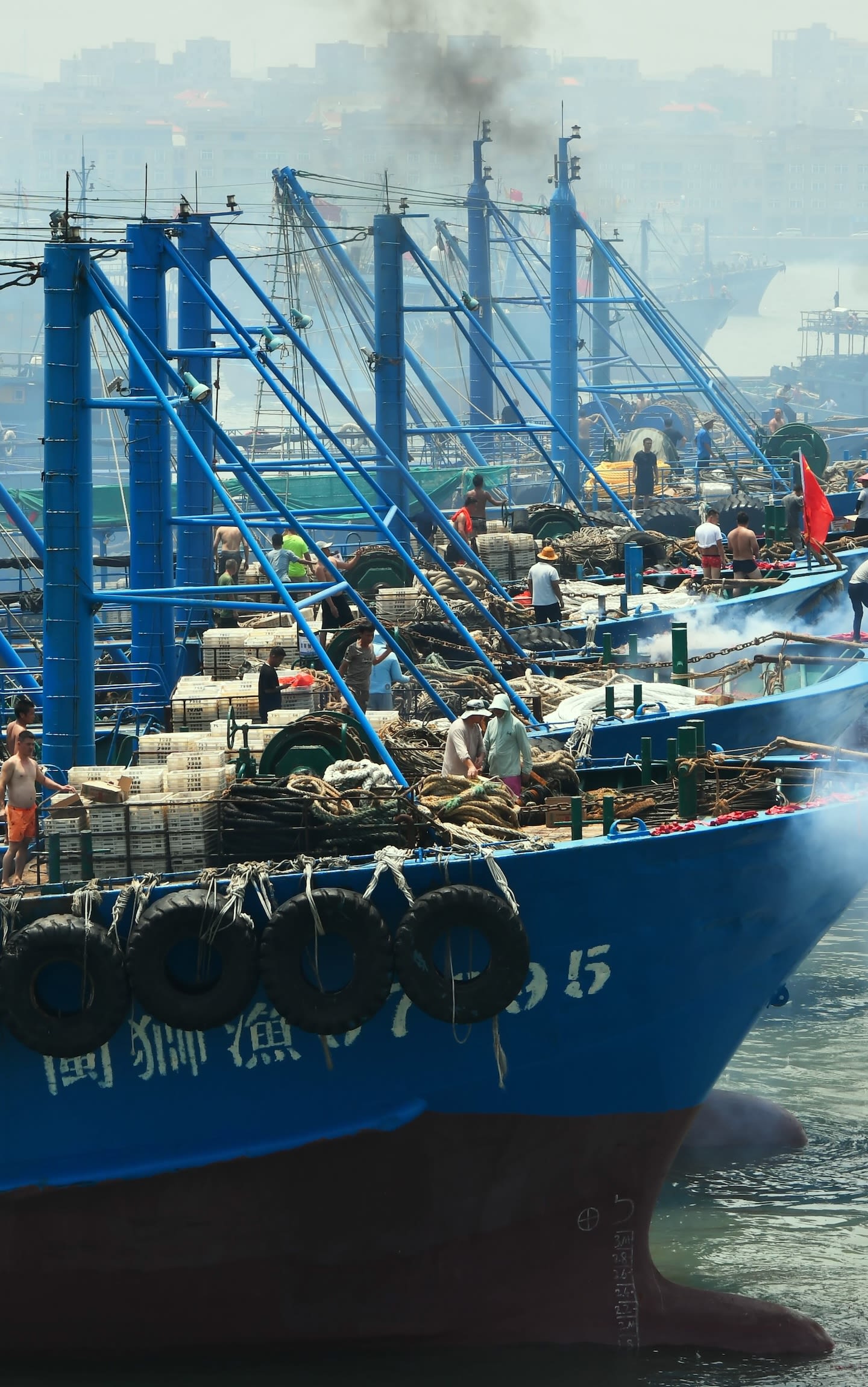 A row of blue fishing trawlers are moored in China before setting sail.