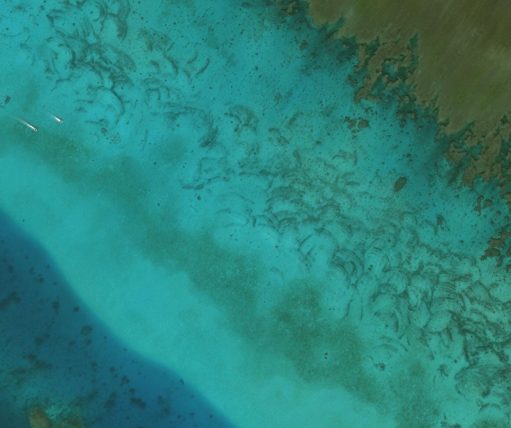Several arc-shaped scars line the shore near Scarborough Shoal.