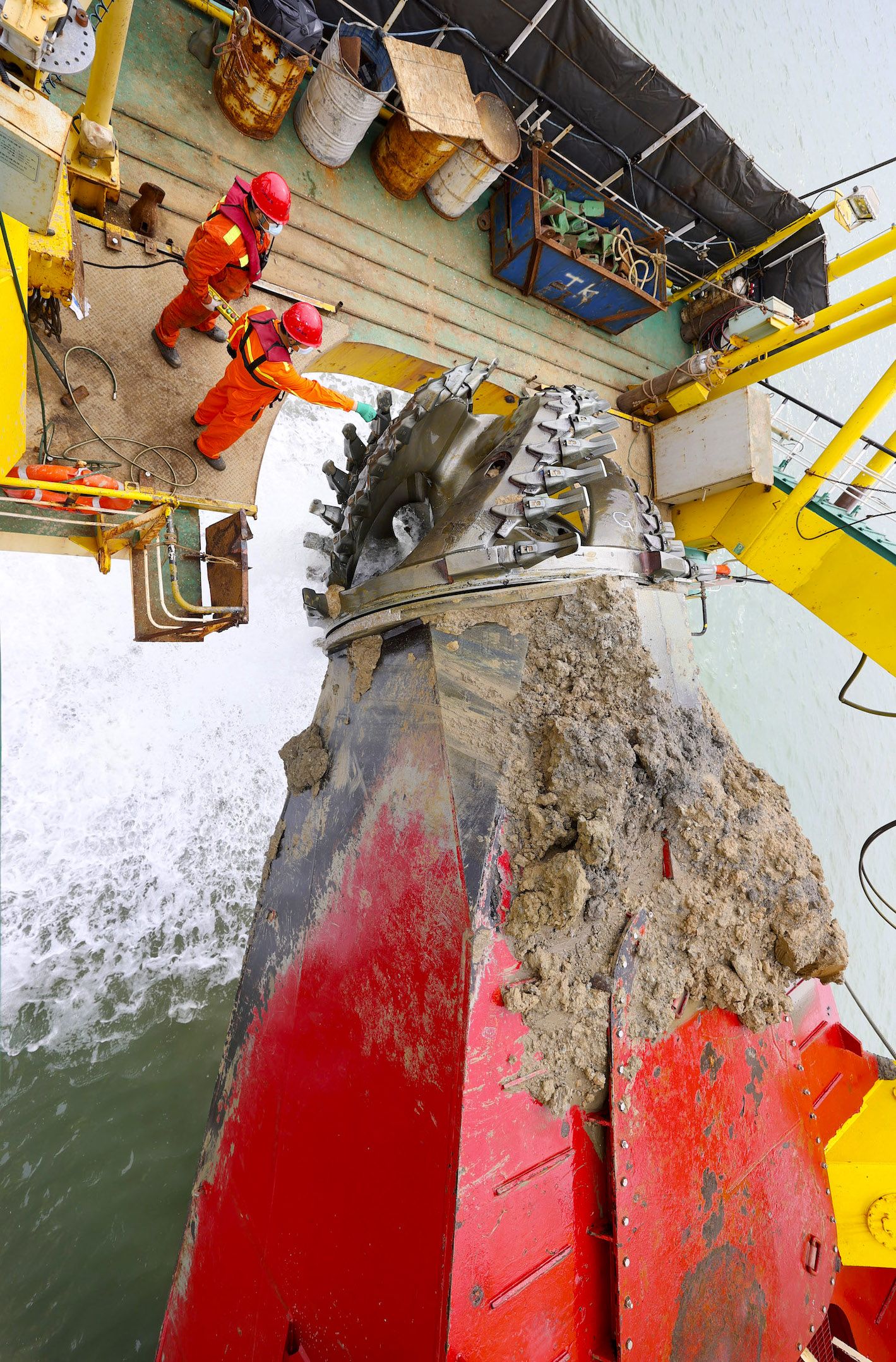 A large machine covered in sediment digs in the ocean.