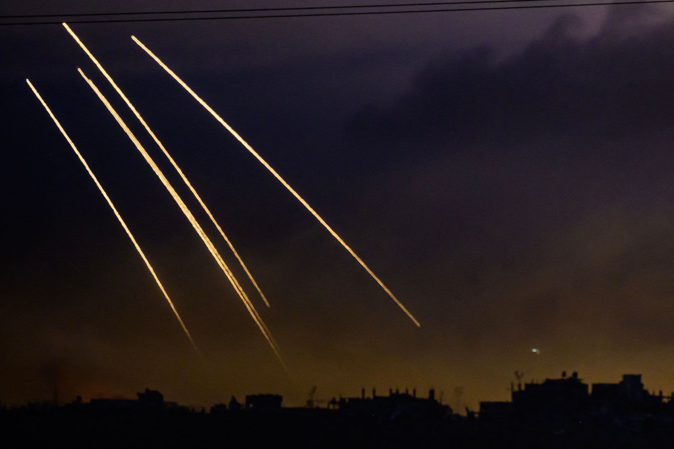 Ammunition falls on a Palestinian enclave under a dark night sky.