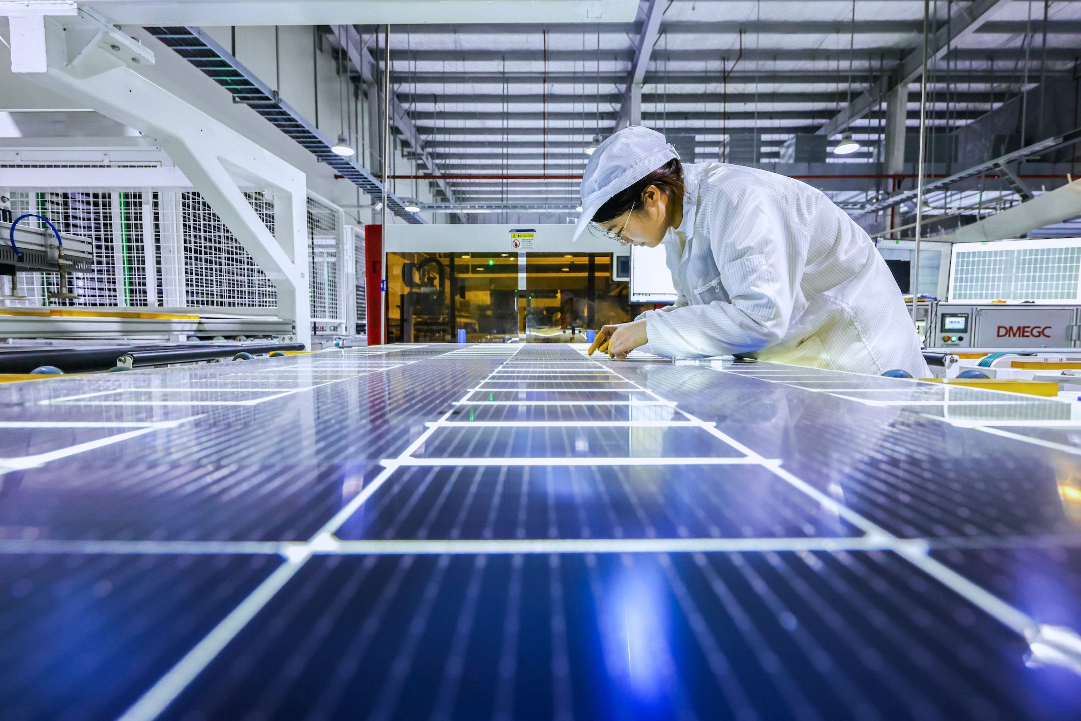 A worker is producing photovoltaic modules for export at a workshop of a new energy company in the Sihong Economic Development Zone in Suqian, Jiangsu Province, China.