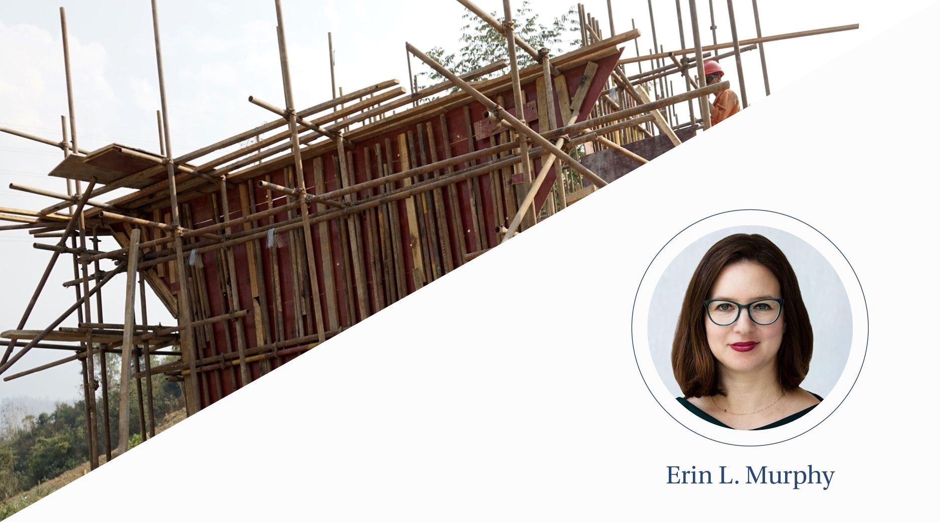 Men in hardhats construct a bamboo structure in a rural area.