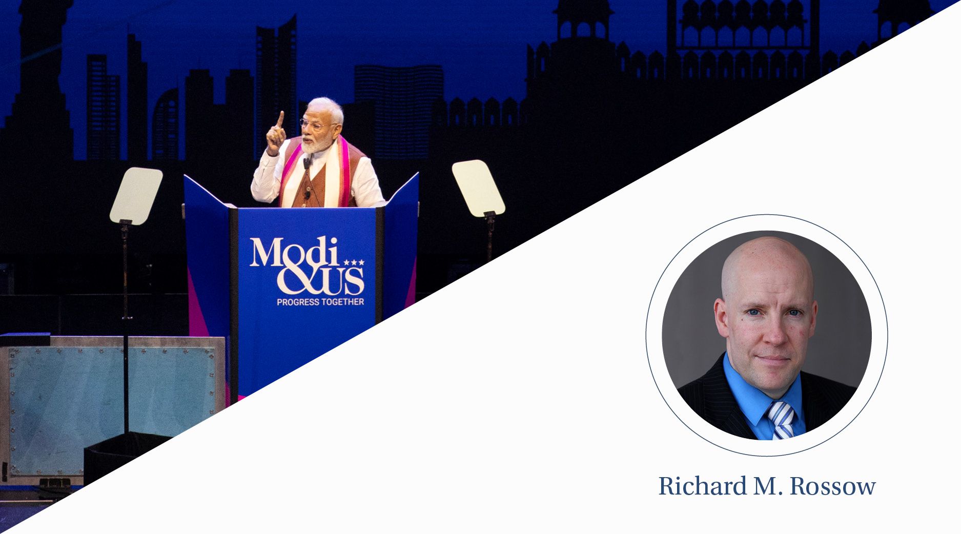 An older Indian man gives a speech in front of a podium.