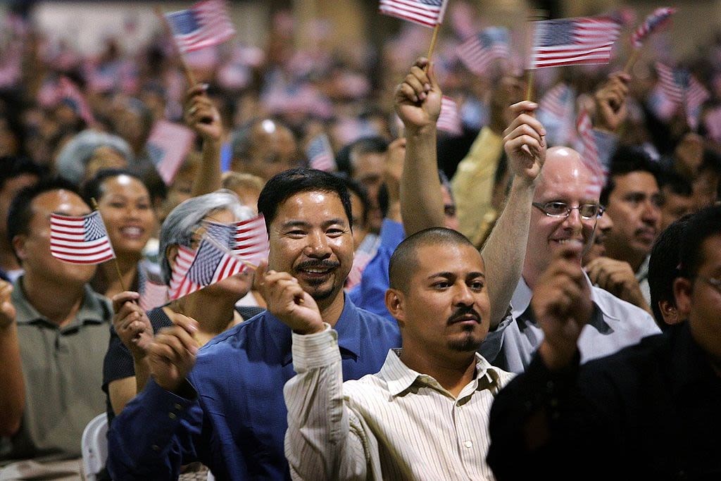 People with smiles wave small American flags in a crowd.