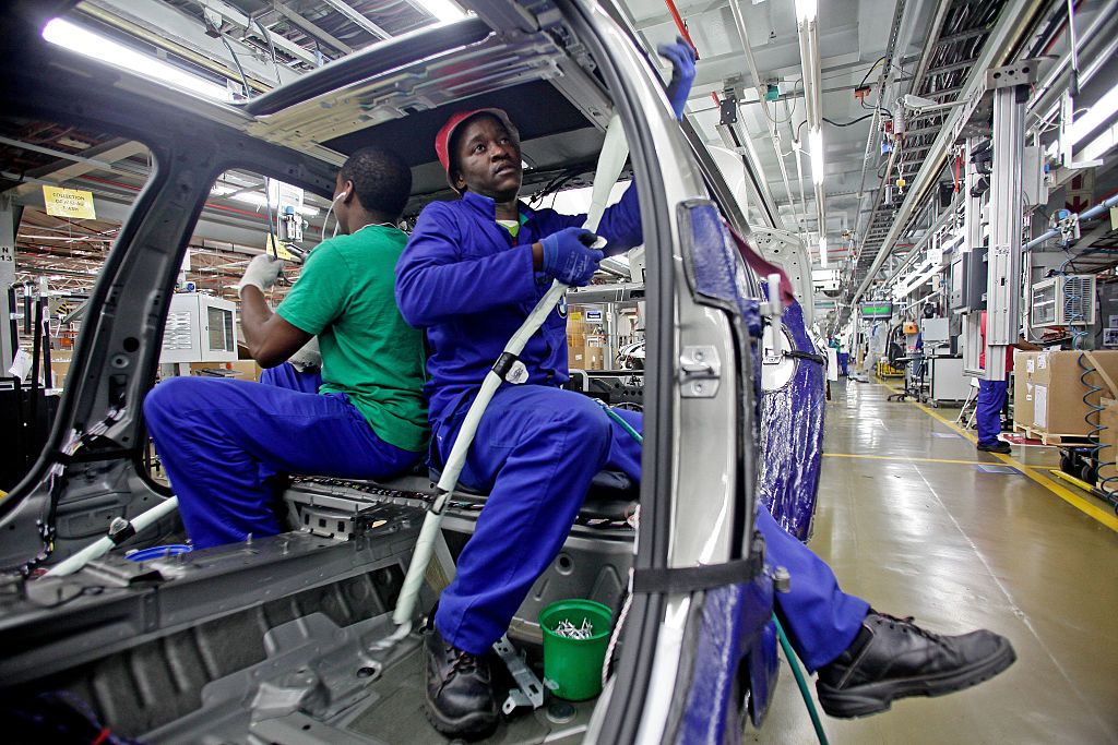 Two men work inside the frame of a car.