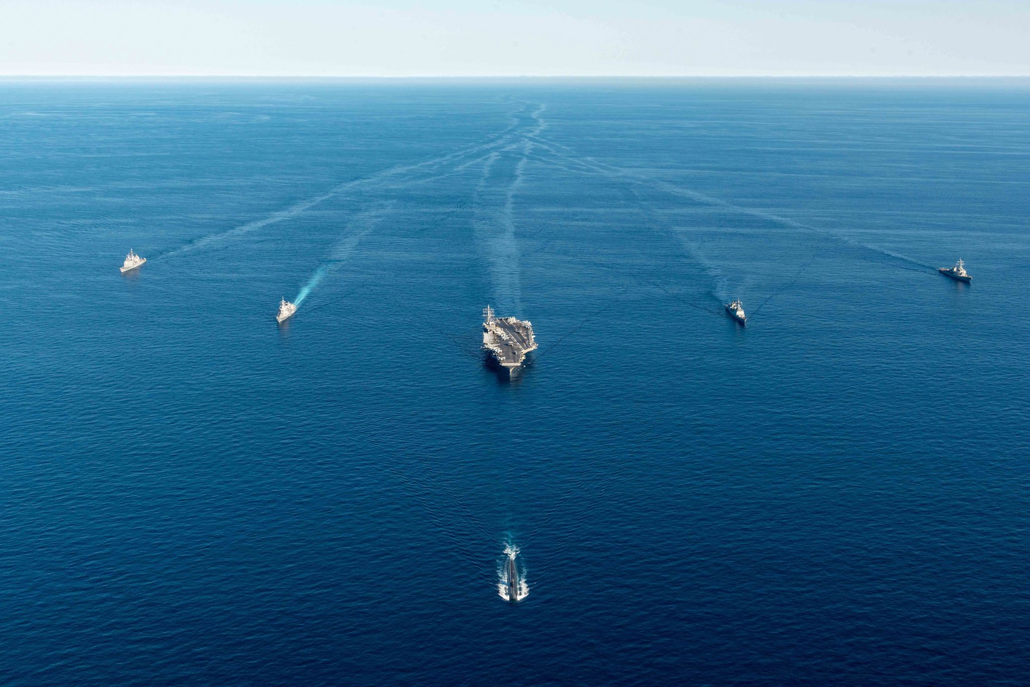 A US aircraft carrier sails in formation in the open ocean with several Japanese and South Korean naval vessels.