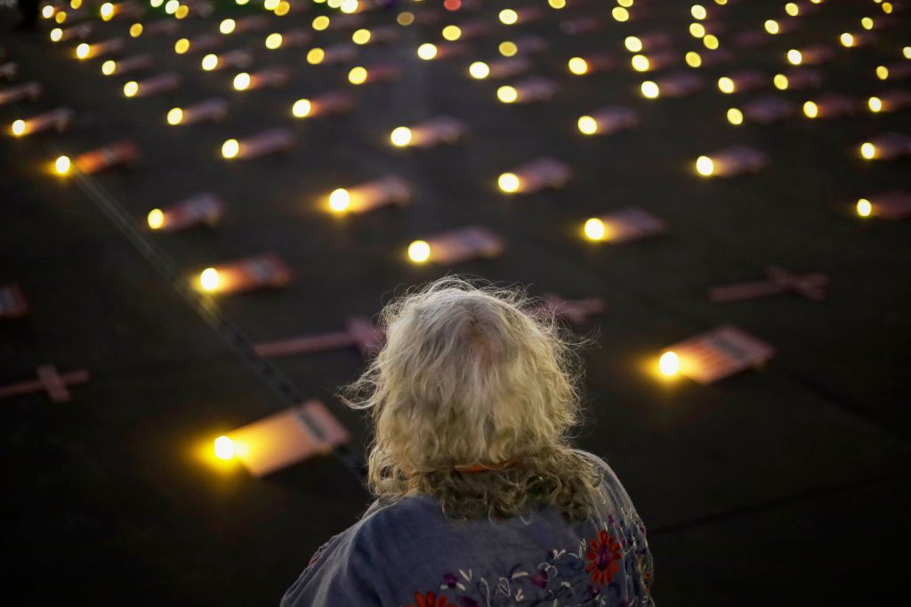 A woman looks at a sea of candle lights on the ground.