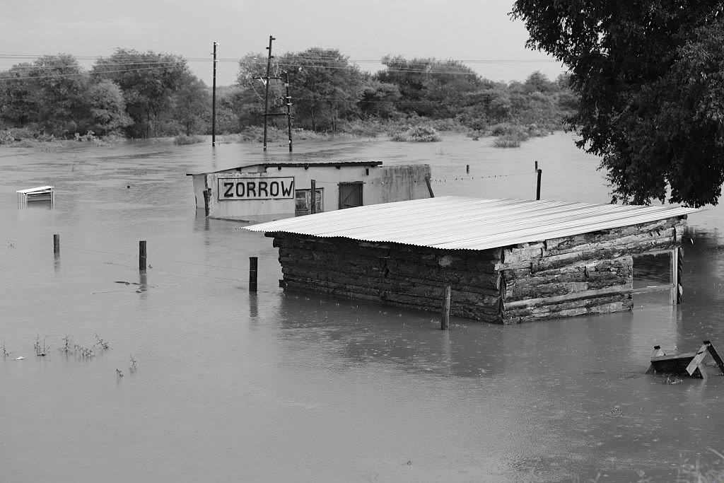 A small building is half submerged in water as rain pours down.