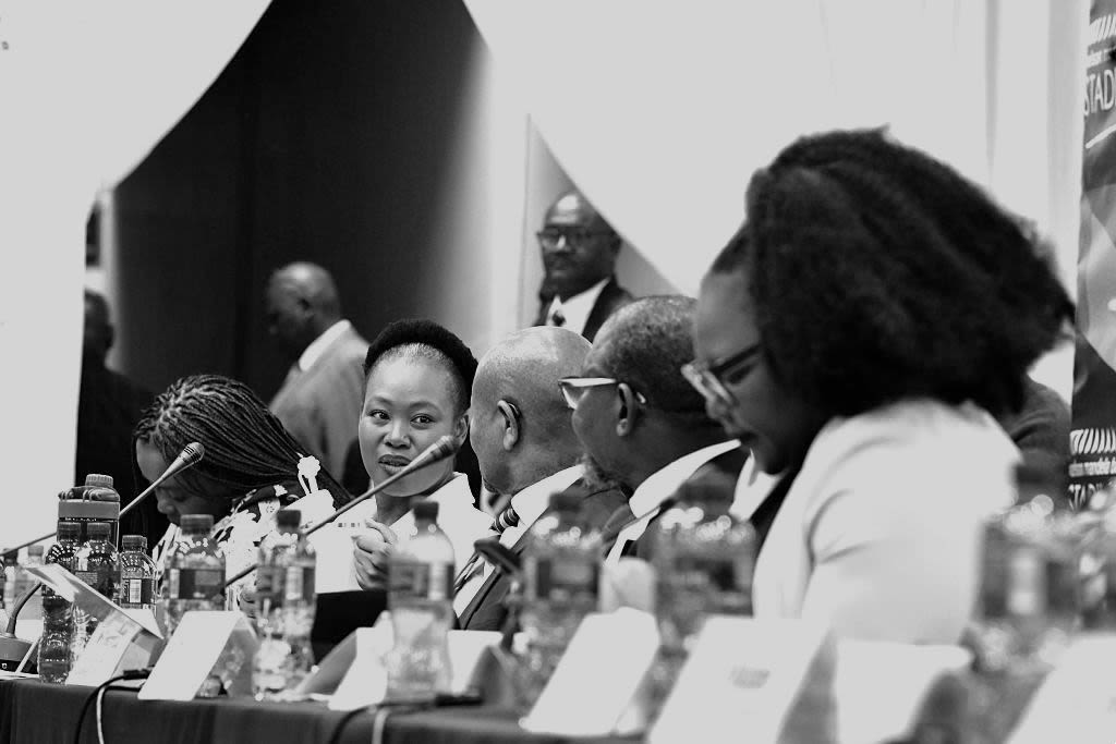 People sit in a line with microphones in front of them.