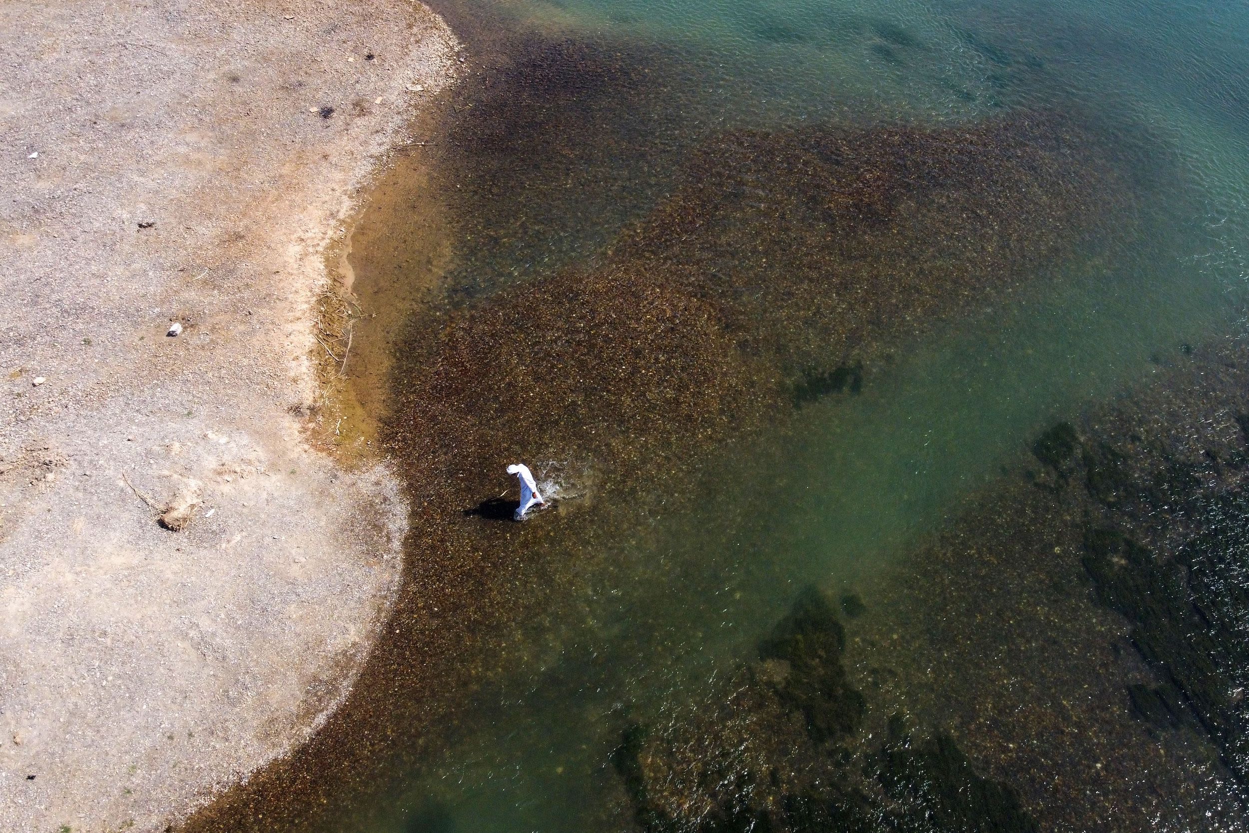 An aerial picture taken by drone shows a man walking on the banks of the Euphrates river in low water levels in the western country side of Raqa on August 5, 2022. (Photo by Delil SOULEIMAN / AFP) 