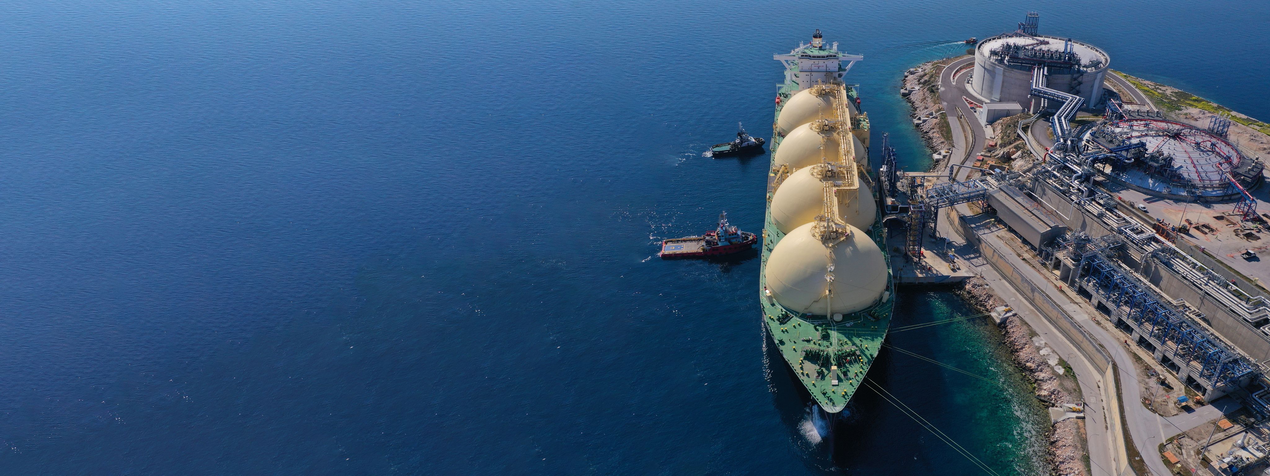 A high-altitude view of an LNG tanker docked at a regasification terminal in Greece