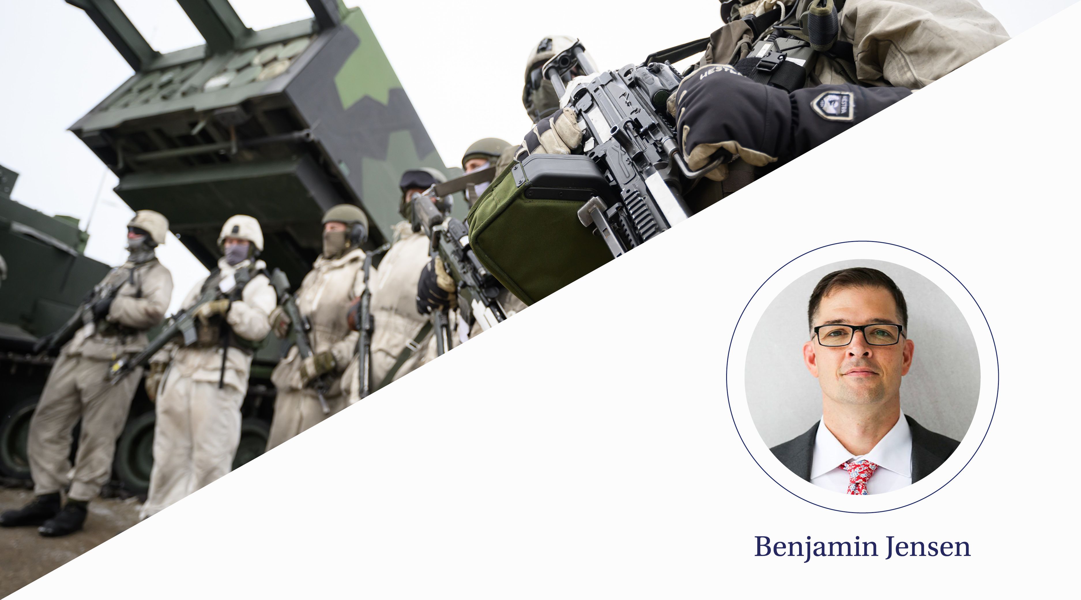 Men dressed in military uniform stand in a row with artillery equipment behind them.